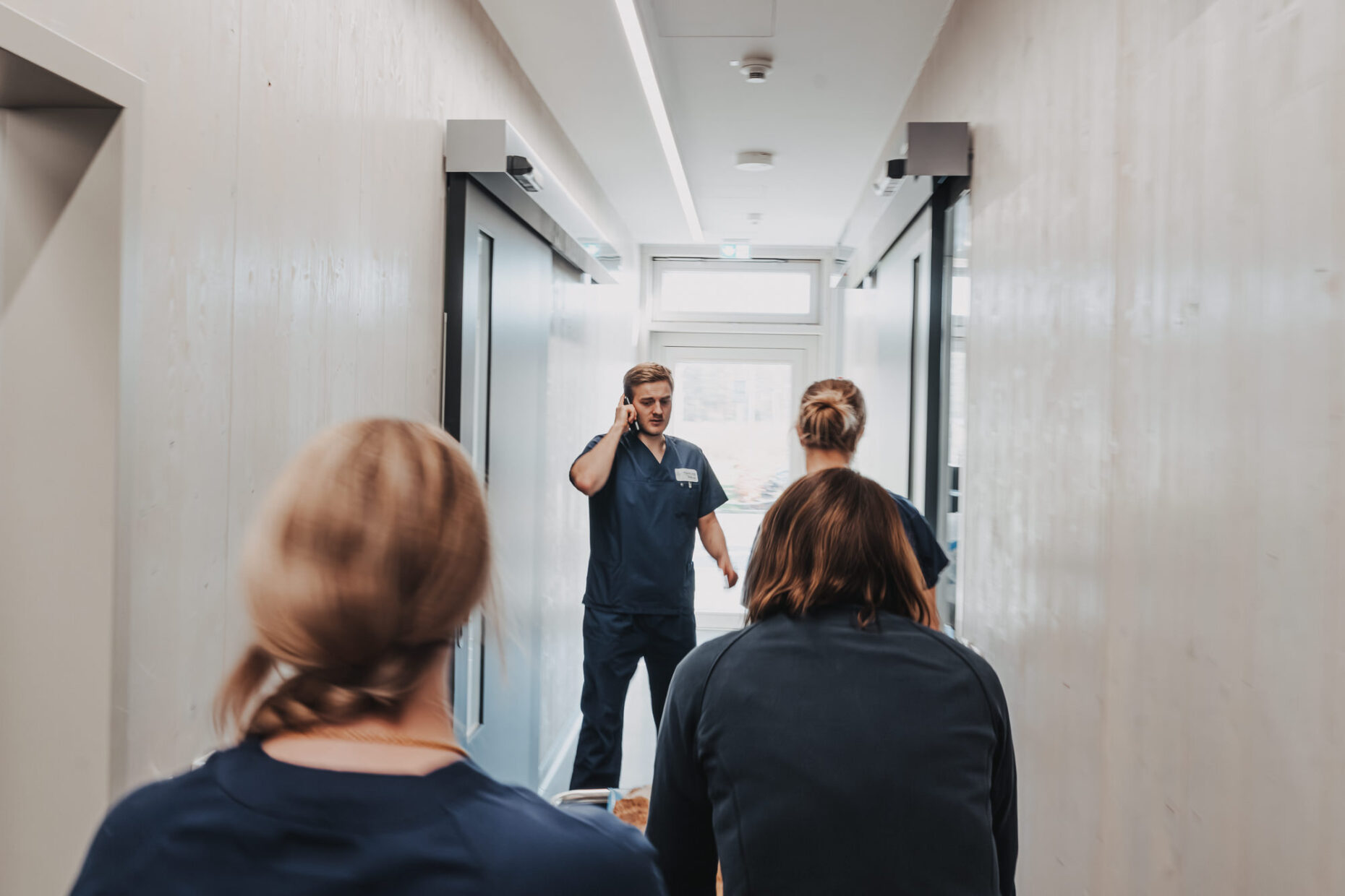 Medizinisches Personal der Tierklinik Posthausen geht durch einen Flur, ein Mitarbeiter telefoniert dabei.